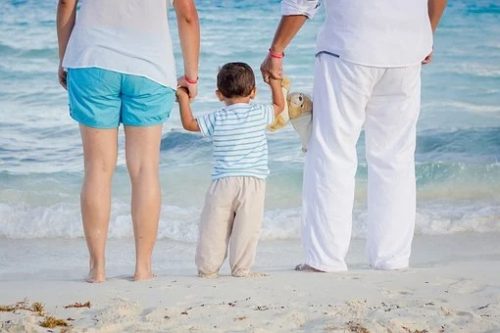 How parents secure kids' mental wellness? A picture of a family in the beach holding hands together.